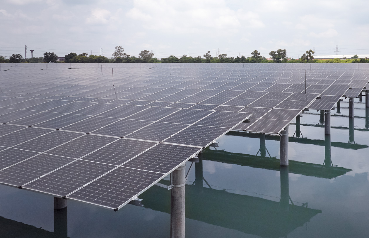 A solar panel array installed over water under a cloudy sky